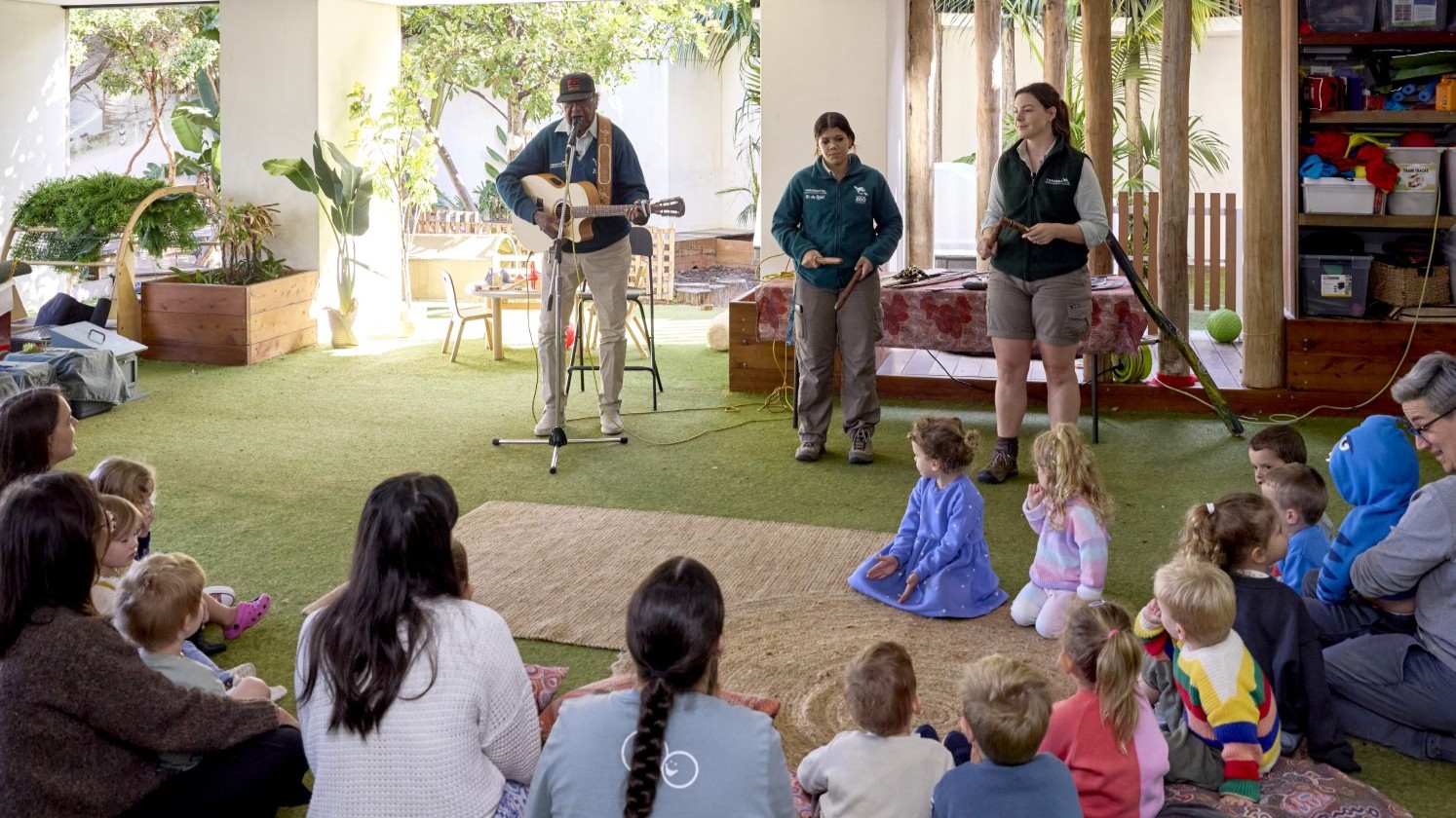 Vacation care group sitting on ground watching Animals of the Dreaming workshop performances by Colin Hardy