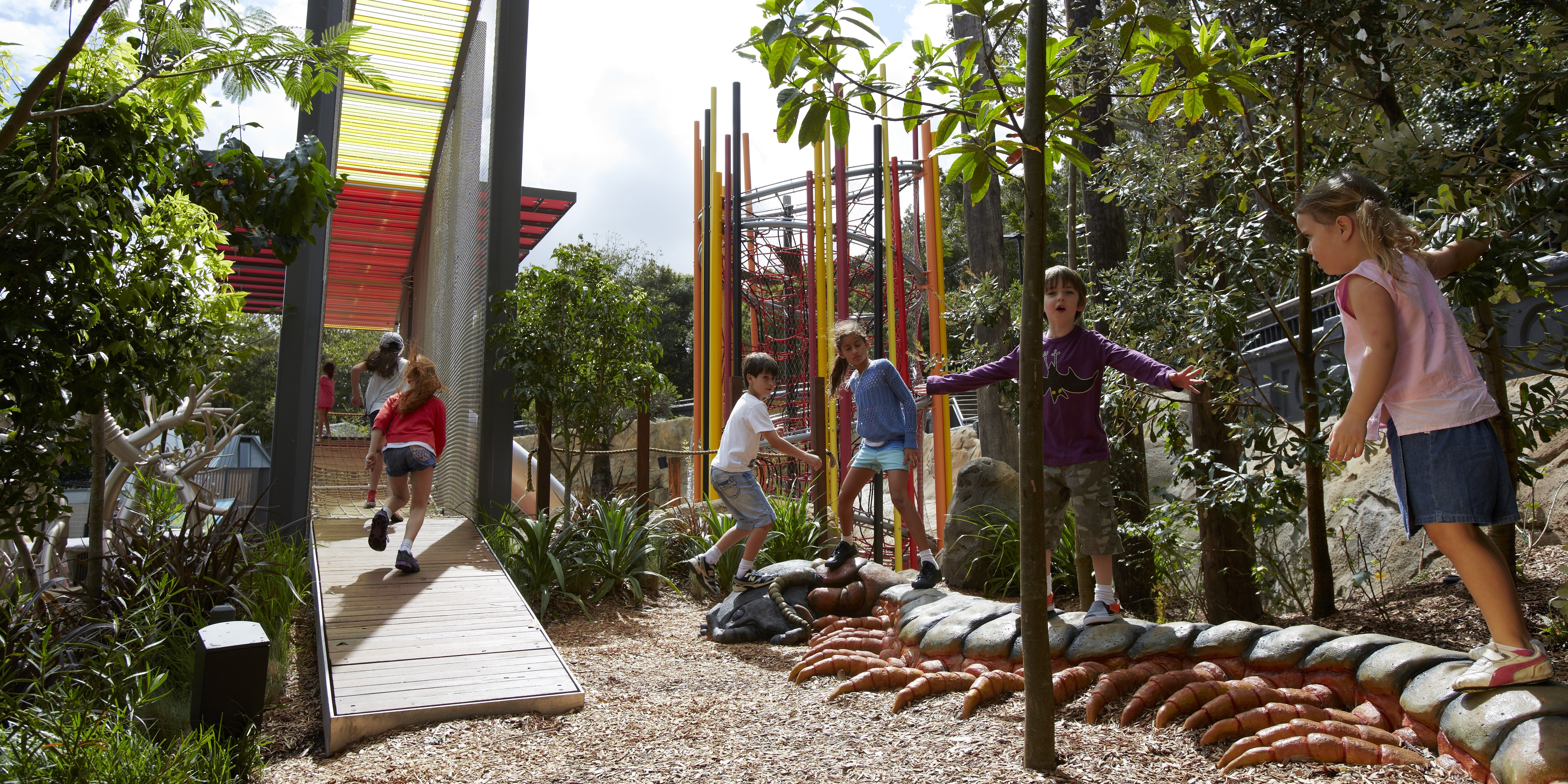 Children playing on a nature-based playground at Taronga Zoo during a vacation care program.