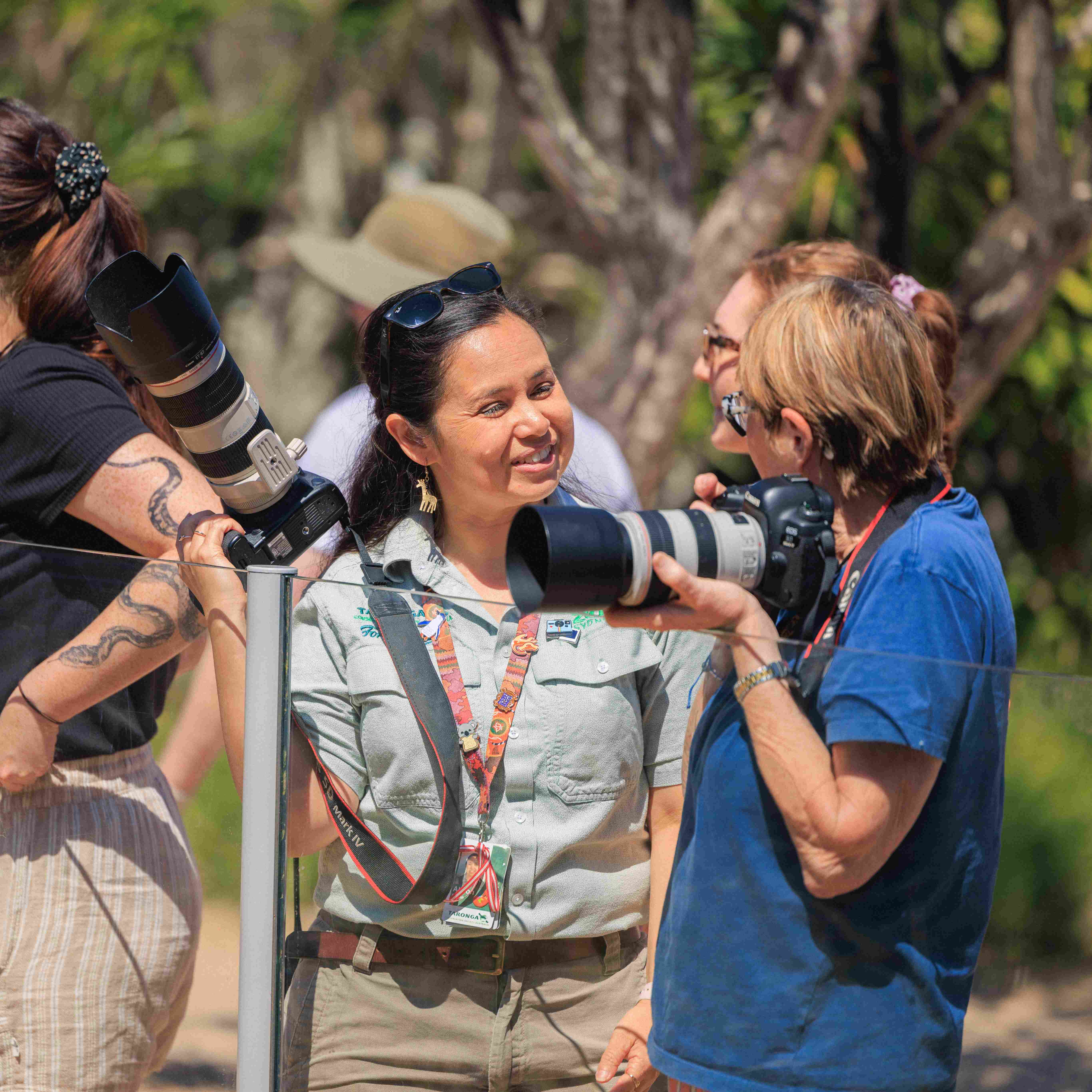 Participants learning photography skills using cameras during an outdoor workshop at the Zoo.